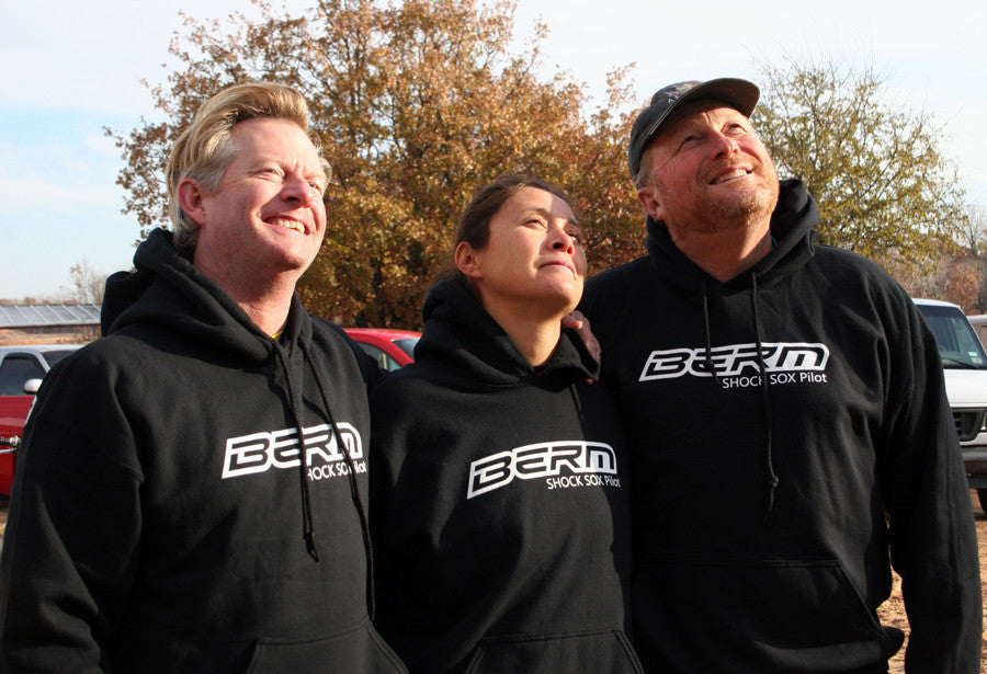 3 people standing next to each other wearing black hoodies with a Berm Shock Sox logo on it