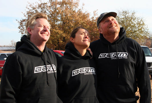3 people standing next to each other wearing black hoodies with a Berm Shock Sox logo on it