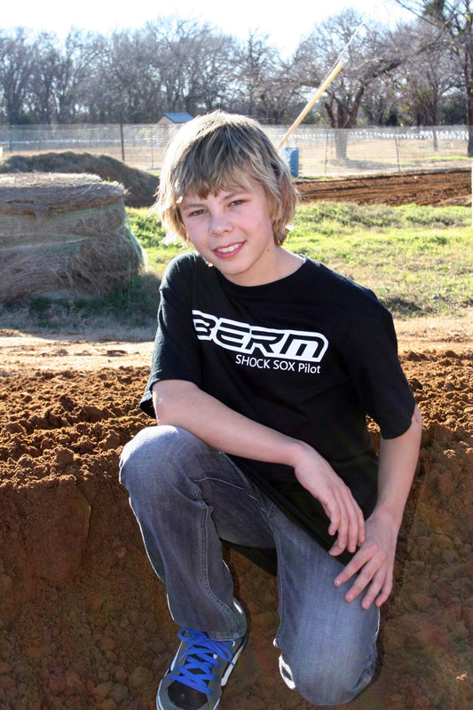 A kid wearing a black shirt that has a BERM Shock Sox logo on it.
