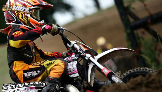 A picture of a kid riding a dirtbike with pink Shock Sox on it.