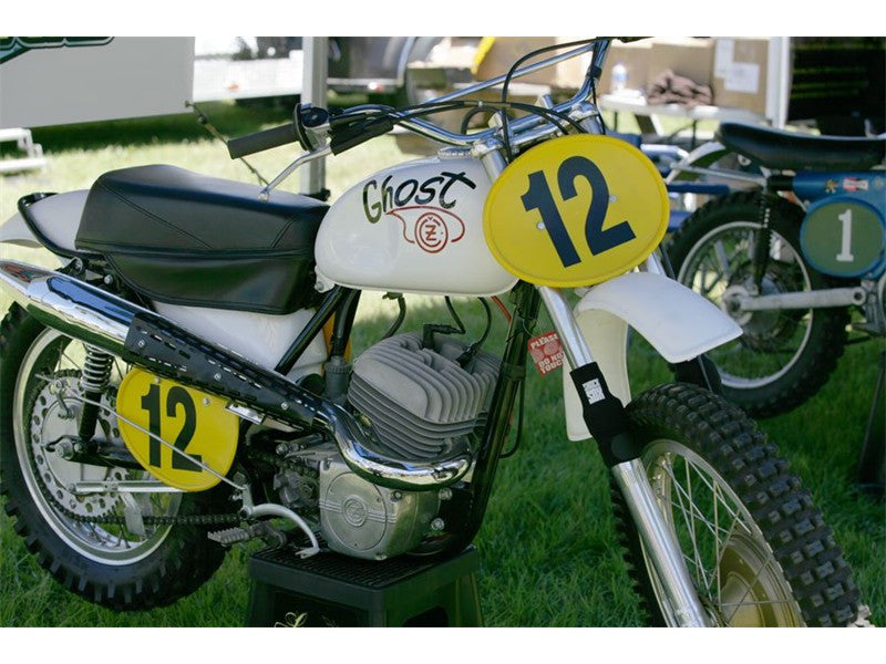 A picture of a vintage dirtbike with black Shock Sox on it.