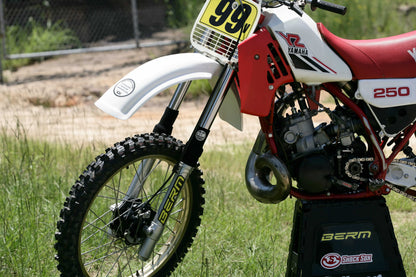 A picture of a vintage dirtbike with black Shock Sox on it.