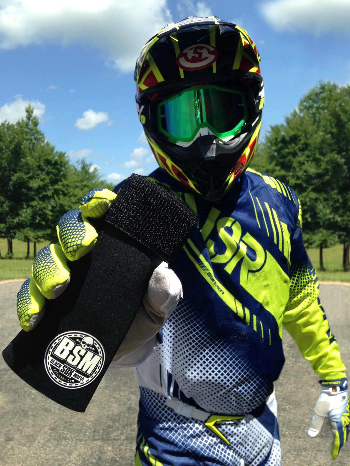 A dirt bike rider in his gear holding black BSM Shock Sox.