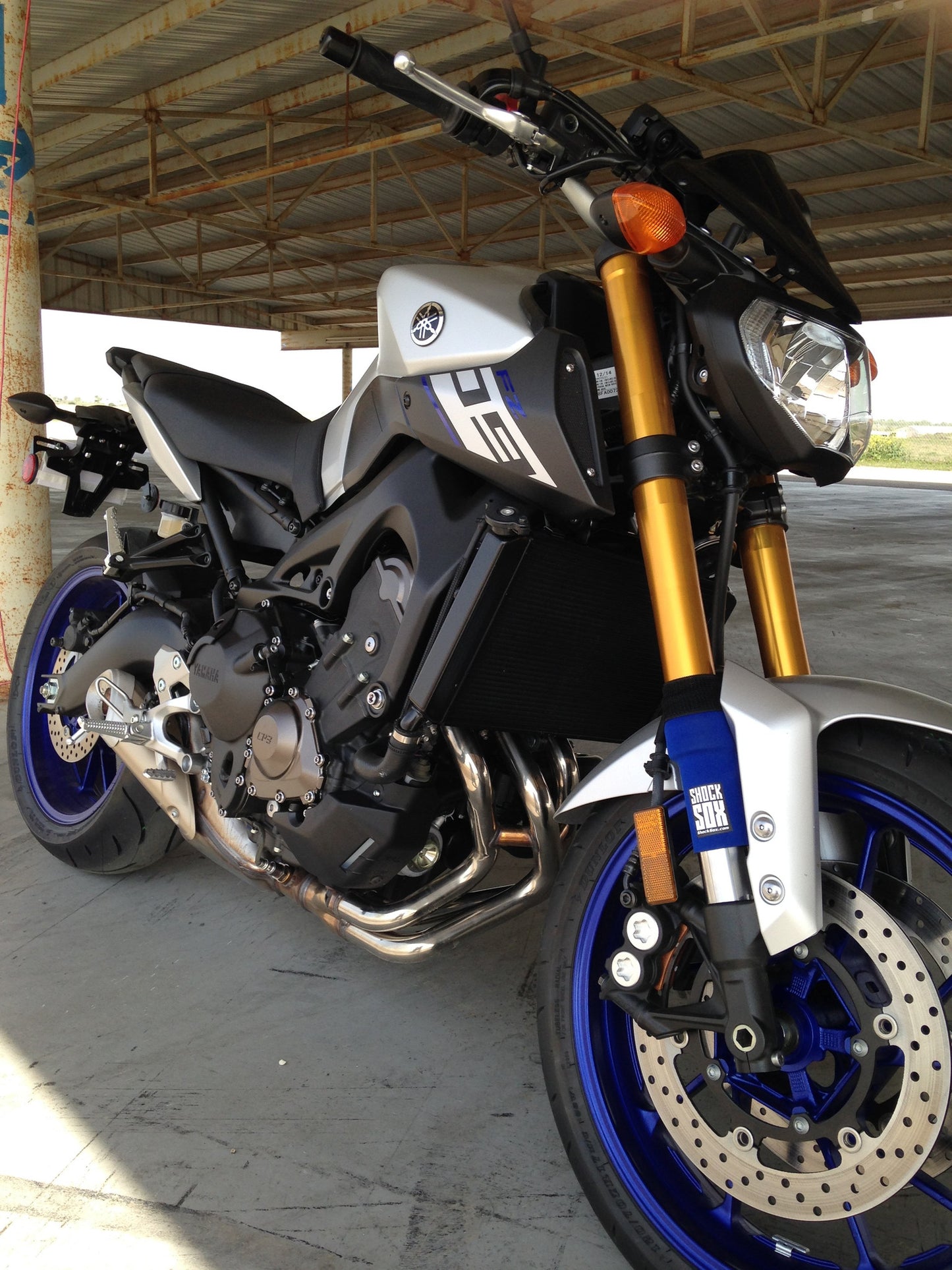 A Yamaha street bike with blue Shock Sox on it.