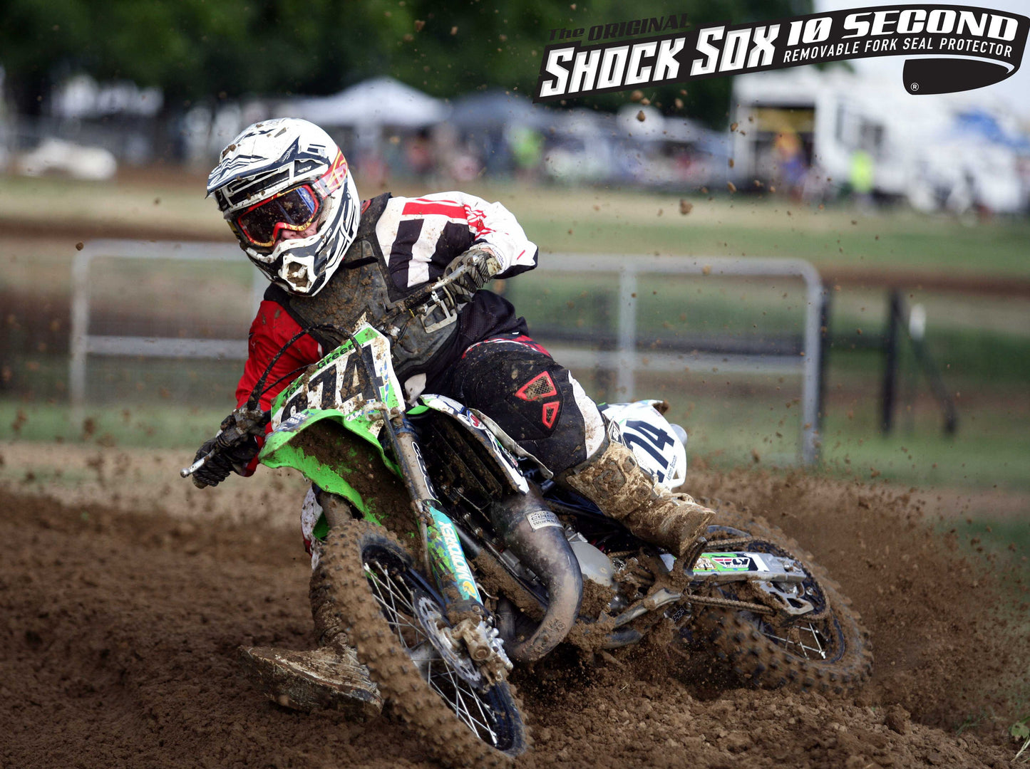 A kid riding a Kawasaki dirt bike with Shock Sox on it.