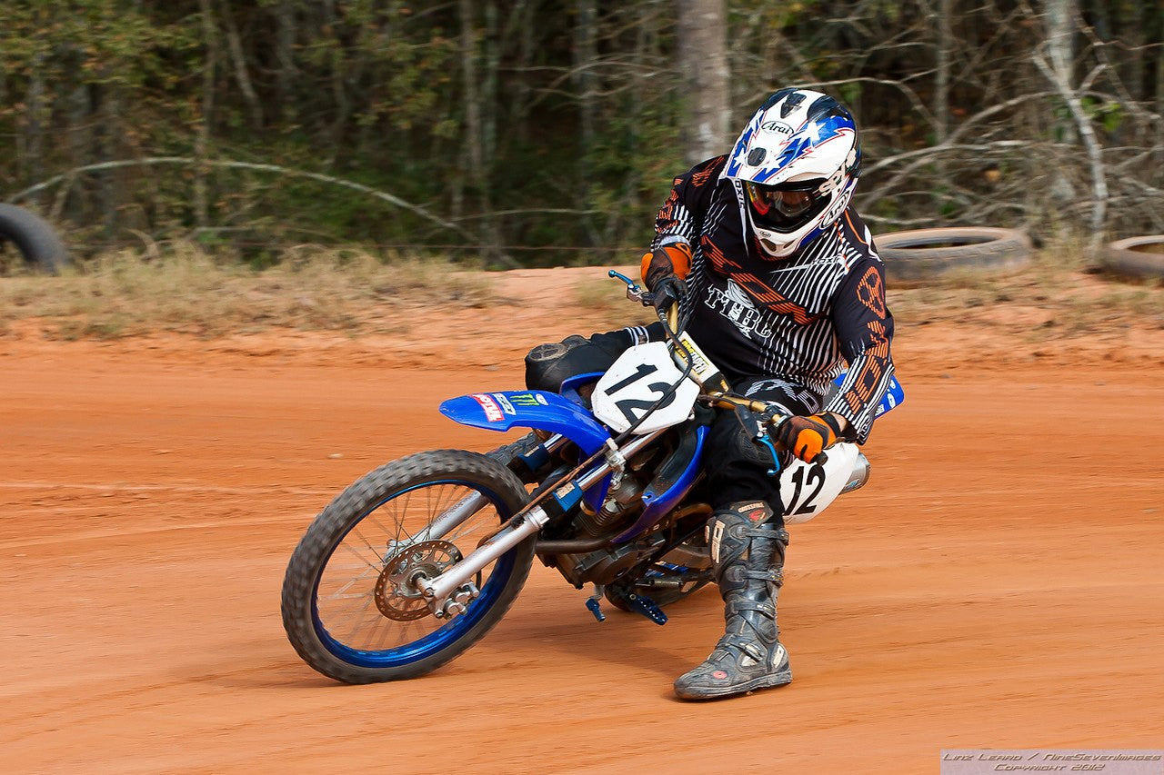 Someone riding a Yamaha dirt bike with blue Shock Sox on it.