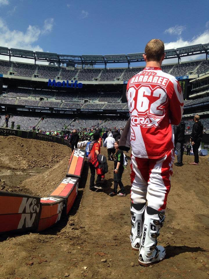 A Shock Sox sponsored rider standing on a Supercross track.