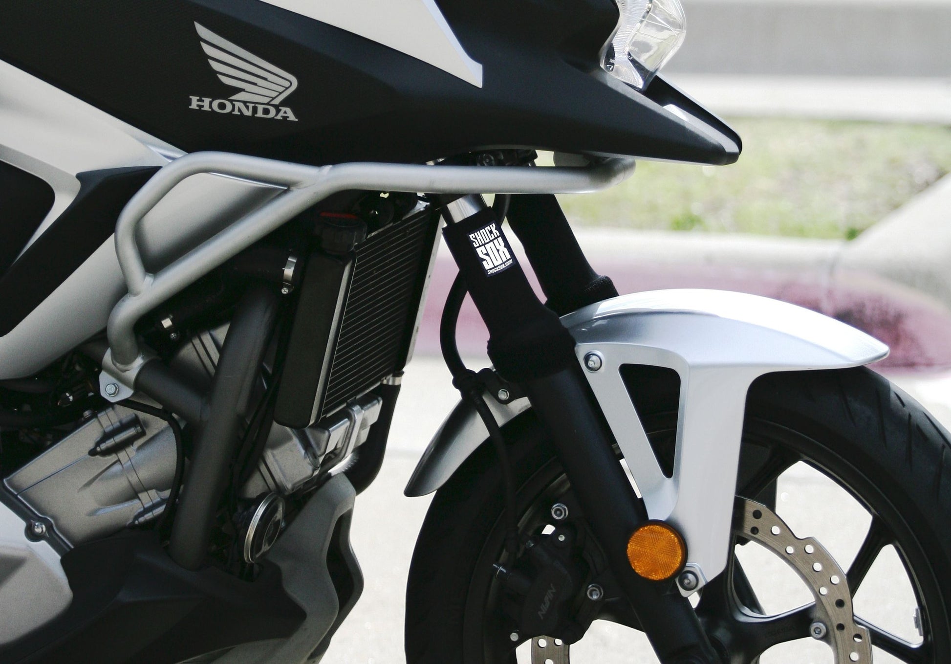 A closeup of a street bike with black Shock Sox on it