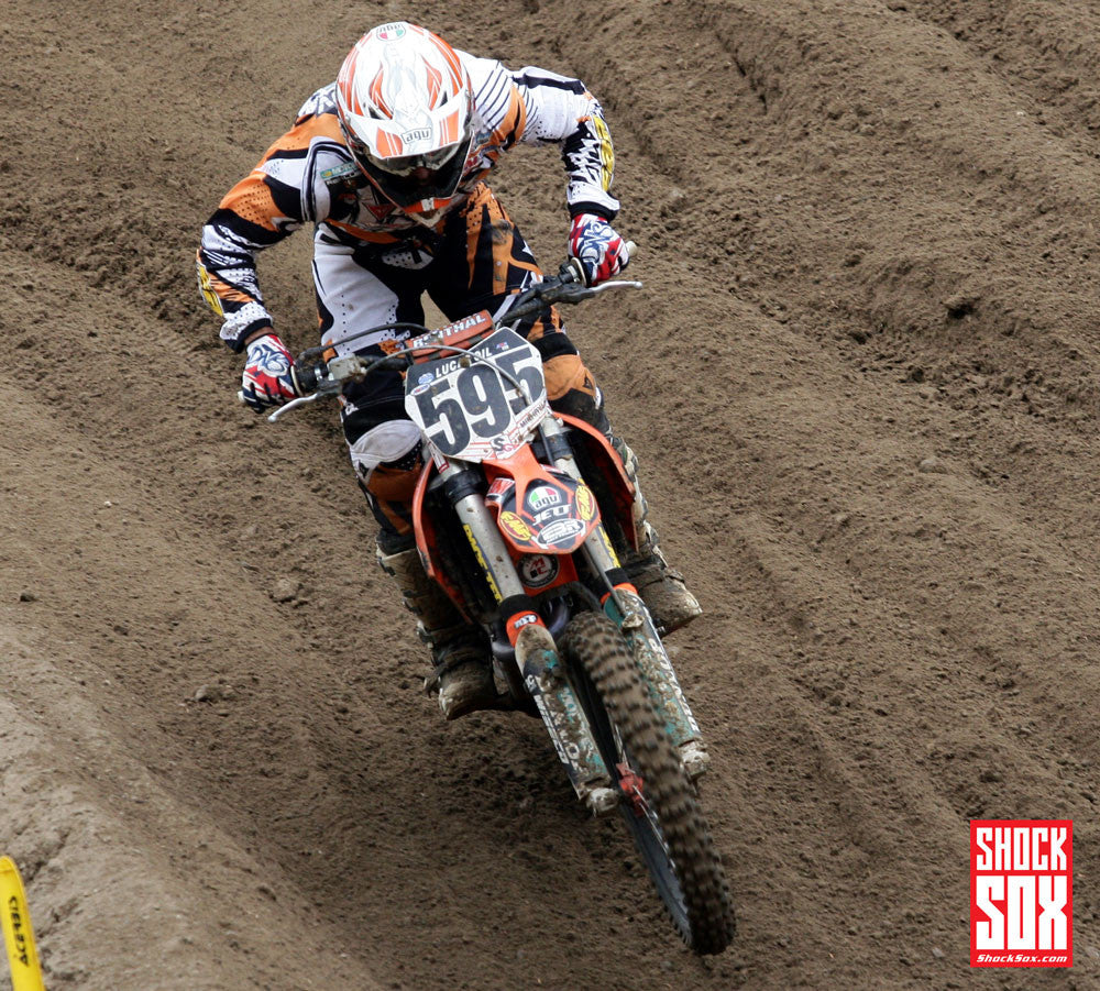 Someone riding a KTM dirt bike with orange Shock Sox on it.