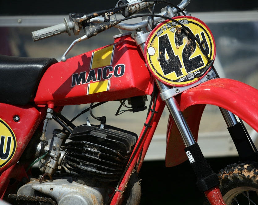 A closeup of a vintage dirtbike with black Shock Sox on it.