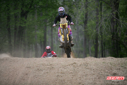 Someone doing a wheelie on a yellow dirtbike with black Shock Sox on it.