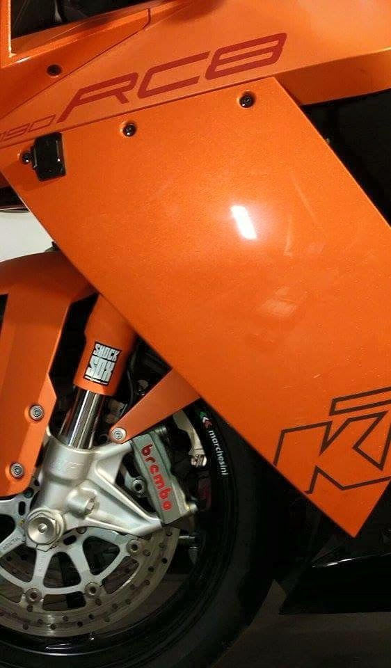 A closeup of a KTM street bike with orange Shock Sox on it.