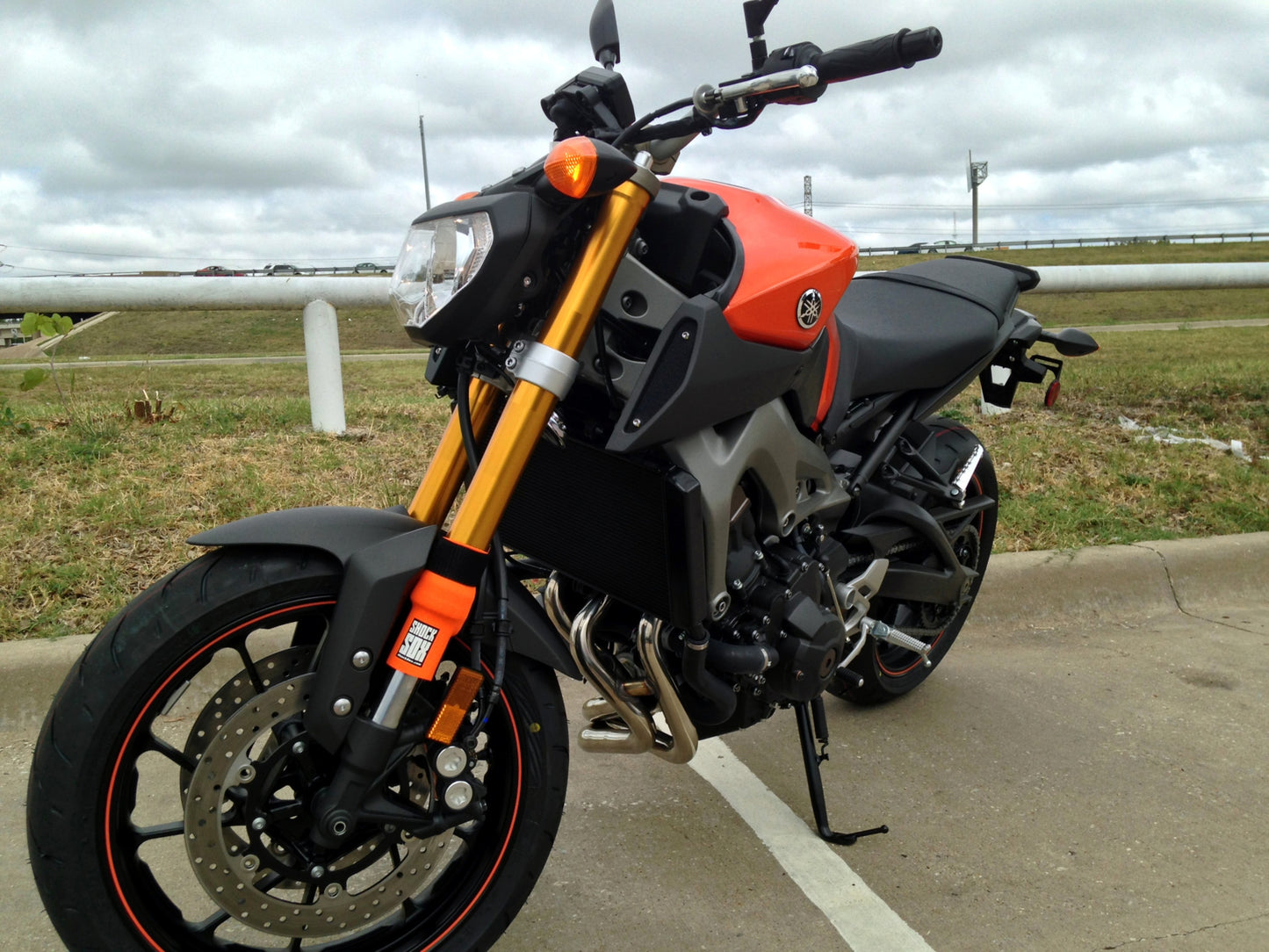A Yamaha street bike with orange Shock Sox on it.