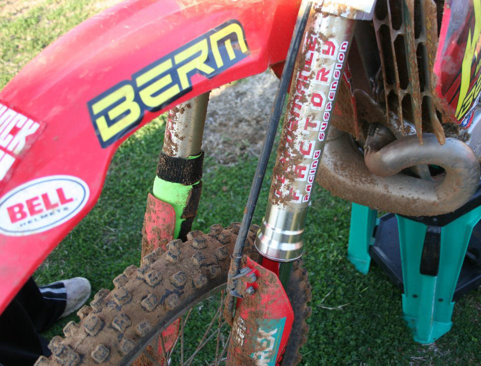 A closeup of a Honda dirt bike with green Shock Sox on it.