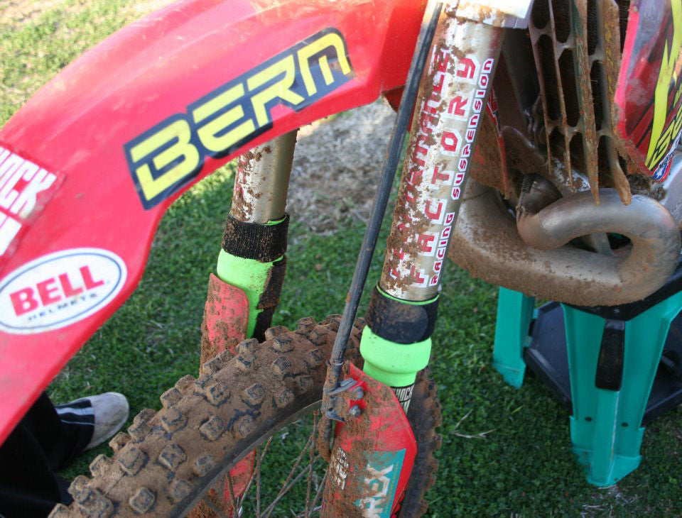 A closeup of a Honda dirt bike with green Shock Sox on it.